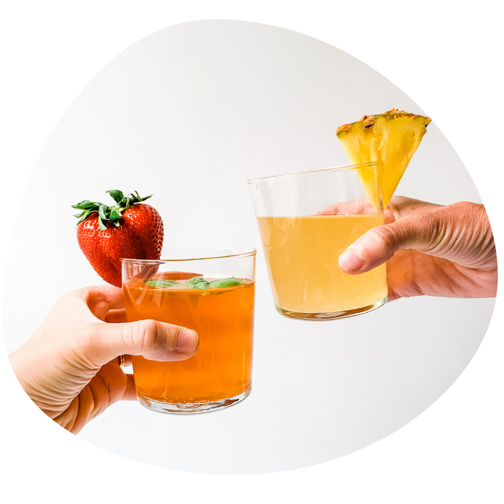 Two hands cheering with glasses of kombucha