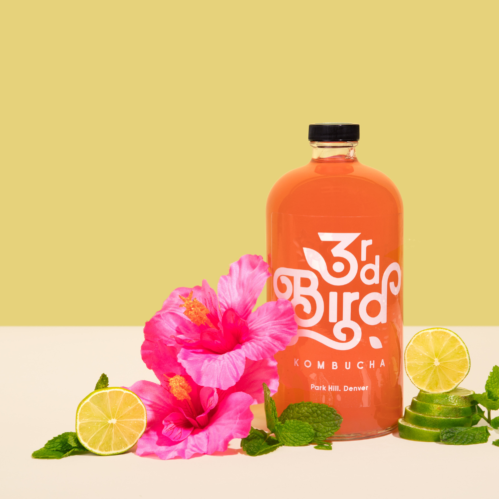 bottle of kombucha with limes and hibiscus flower