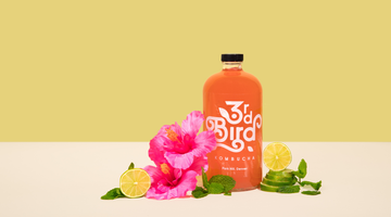 bottle of kombucha with limes and hibiscus flower