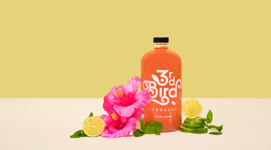 bottle of kombucha with limes and hibiscus flower