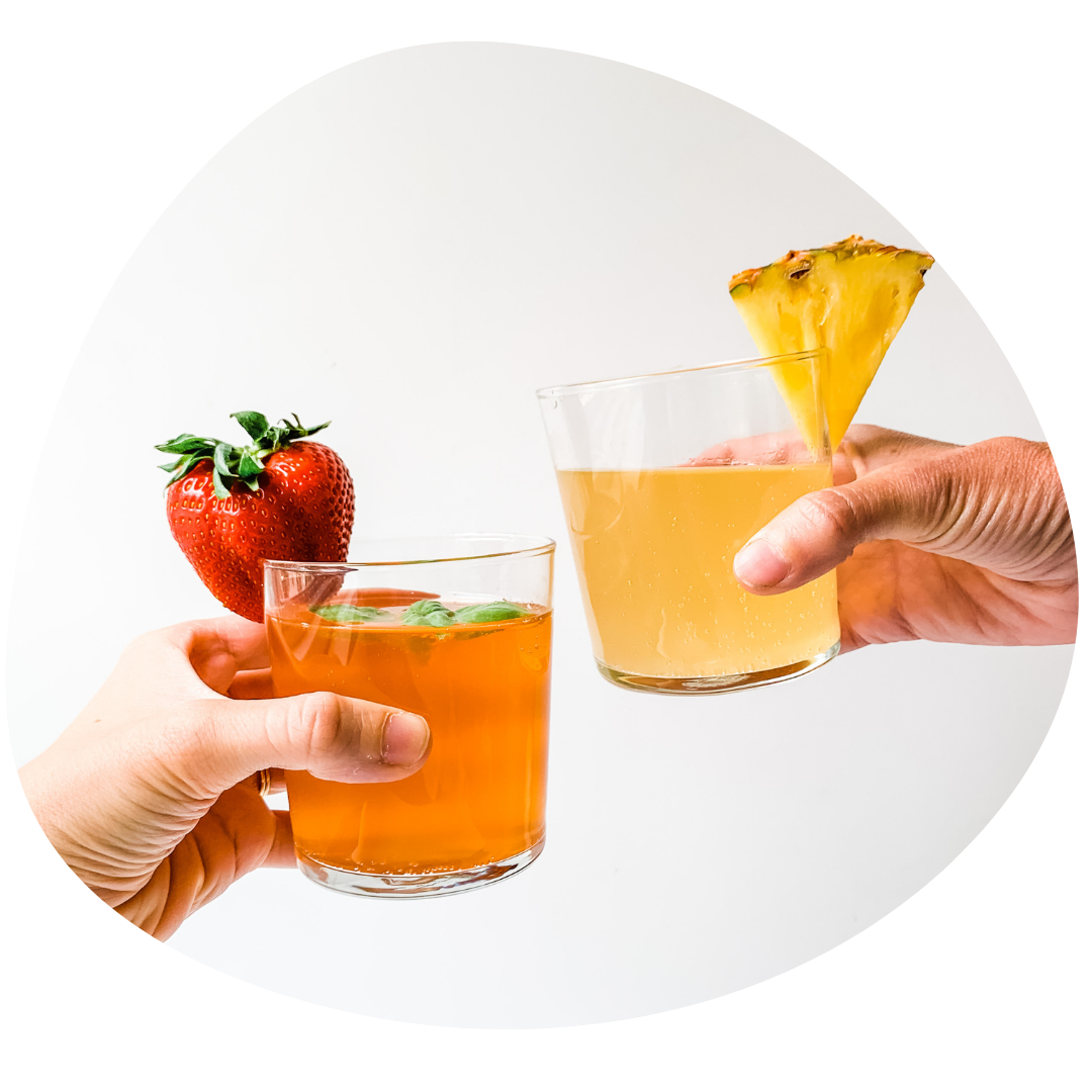 Two hands cheering with glasses of kombucha