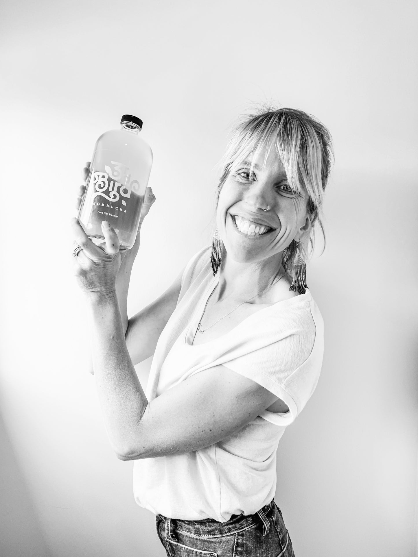 Woman smiling holding bottle of kombucha