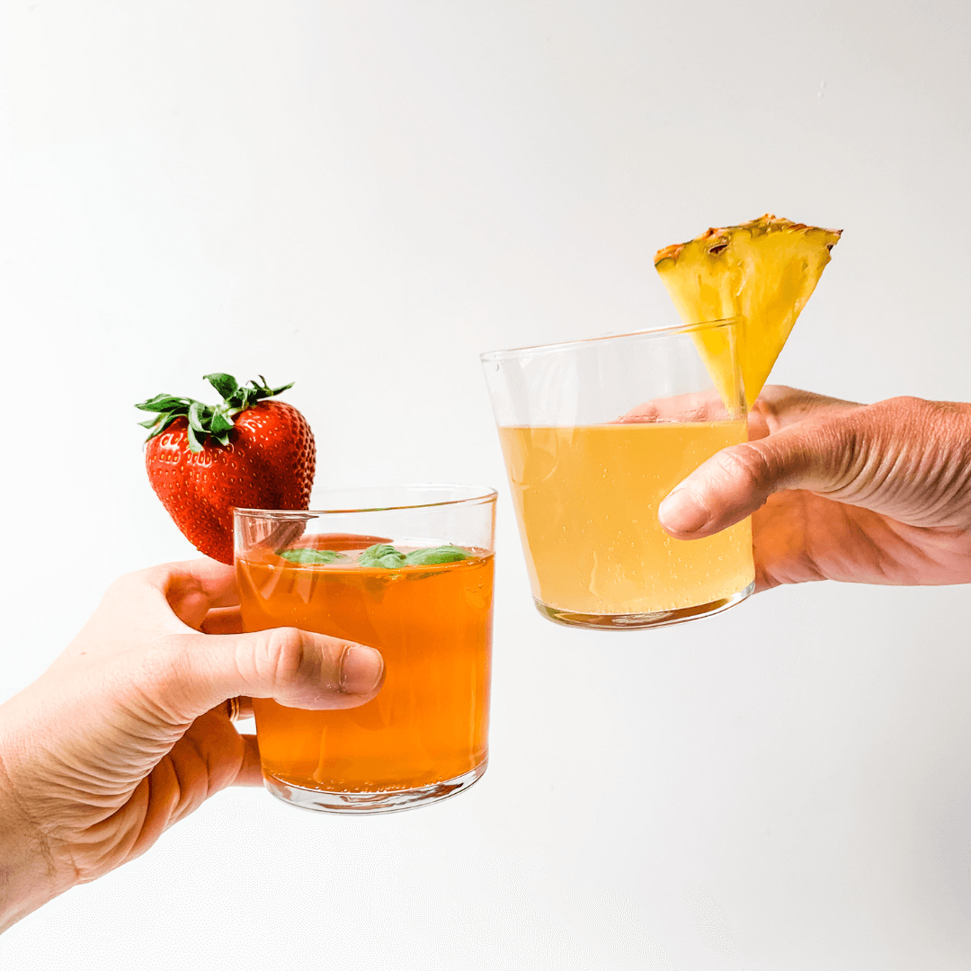 two glasses of kombucha cheering eachother